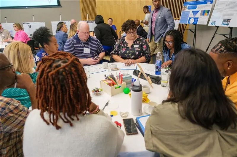 A group of KC Health Equity LAN members sitting around a table in a room at the Kauffman Foundation