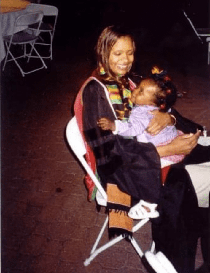 Tiana Ford de niña sentada en el regazo de su madre en su graduación de la facultad de medicina.