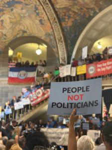 Someone holding up a "People Not Politicians" sign being held up at the Missouri State Capital.